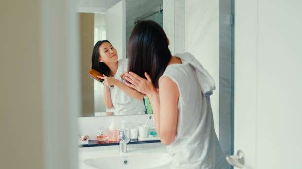 Young Asian woman having fun combing her beautiful hair in hair oil