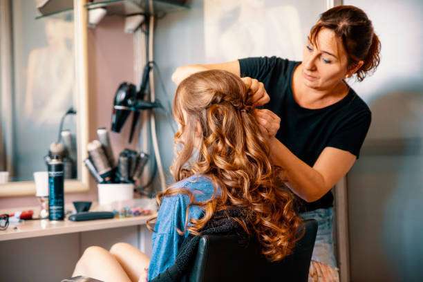 A lady dripping hair oil with a pipette on her hair.