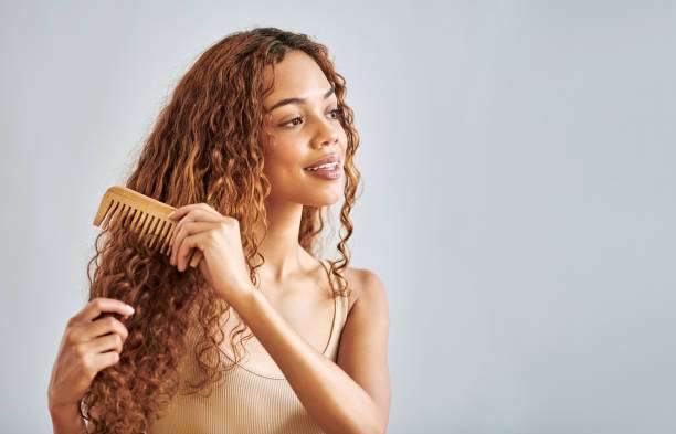 A lady dripping hair oil with a pipette on her hair.