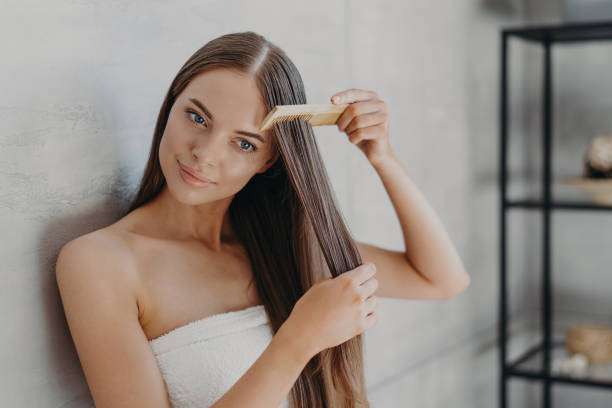 A lady dripping hair oil with a pipette on her hair.