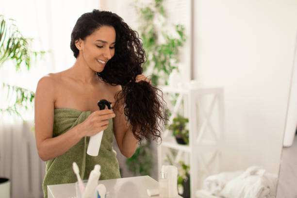 A lady dripping hair oil with a pipette on her hair.