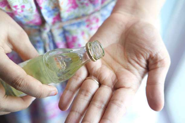 pouring hair oil on hand close up.