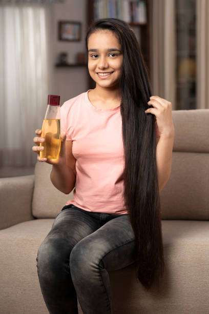 A lady dripping hair oil with a pipette on her hair.