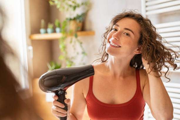 A lady dripping hair oil with a pipette on her hair.