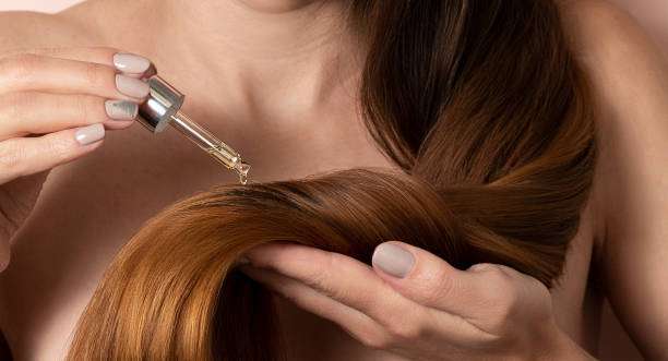 hair oil with a pipette on her hair.