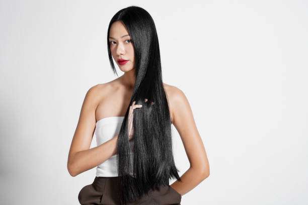 Woman applying hair oil to her long braided hair.