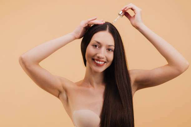 Young female adult standing in front of mirror in the bathroom at home after washing her hair oil