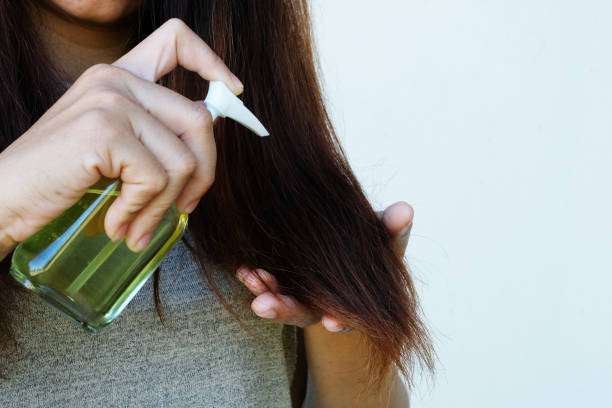 Applying hair oil with a spray bottle for healthy shine and growth.