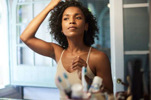 Woman applies hair oil for healthy, shiny hair.