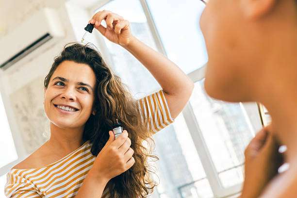 Woman smiling applying hair oil to wavy dark hair