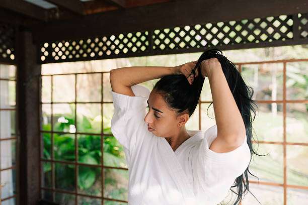 Woman tying her dark hair up, ready for treatment.