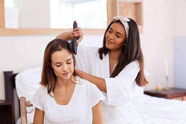 Young female adult standing in front of mirror in the bathroom at home after washing her hair oil