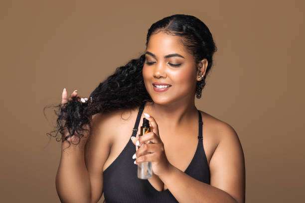 Woman applying hair oil to her healthy, long hair.