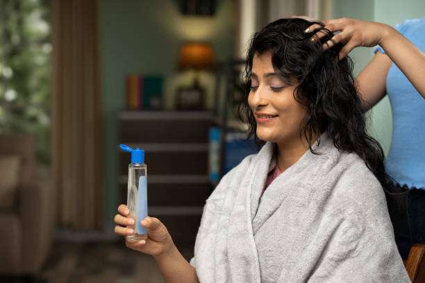 Woman applying hair oil to her healthy, long hair.