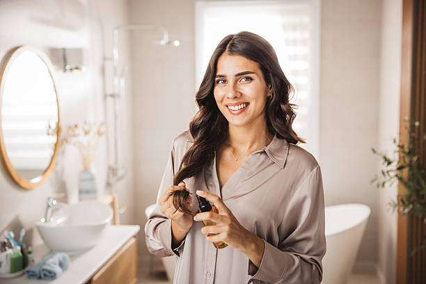 Young woman styling her hair in front of a mirror.