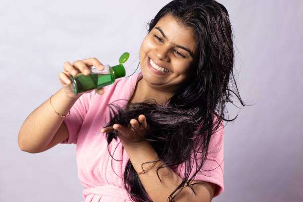 Young female adult standing in front of mirror in the bathroom at home after washing her hair oil