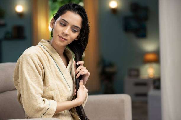 Young female adult standing in front of mirror in the bathroom at home after washing her hair oil