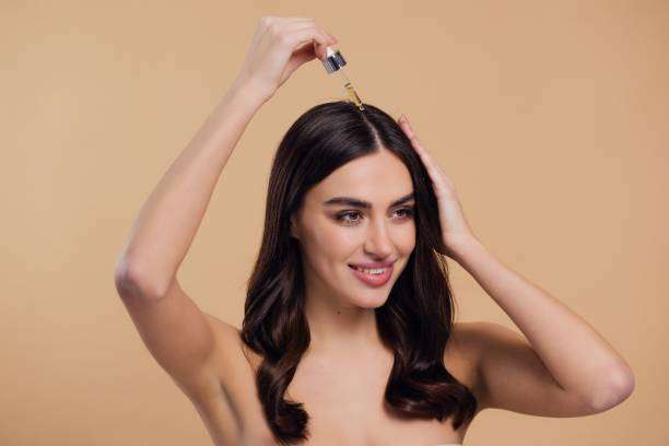 Young female adult standing in front of mirror in the bathroom at home after washing her hair oil