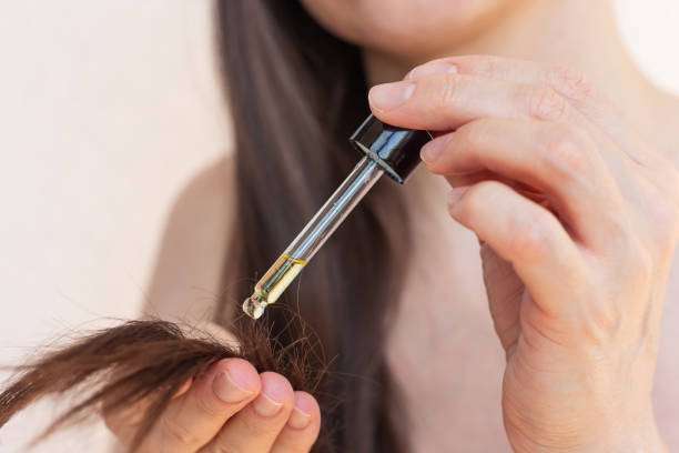 Close-up of hair oil being applied to split ends for repair and hydration.