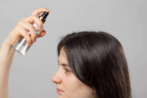 Spraying hair oil mist for instant shine and frizz control.