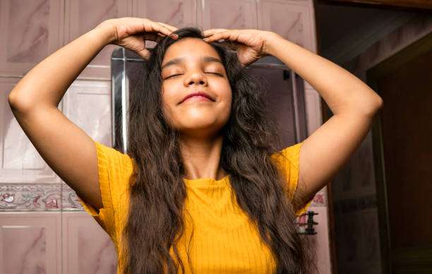 Young woman massaging scalp with hair oil for growth.
