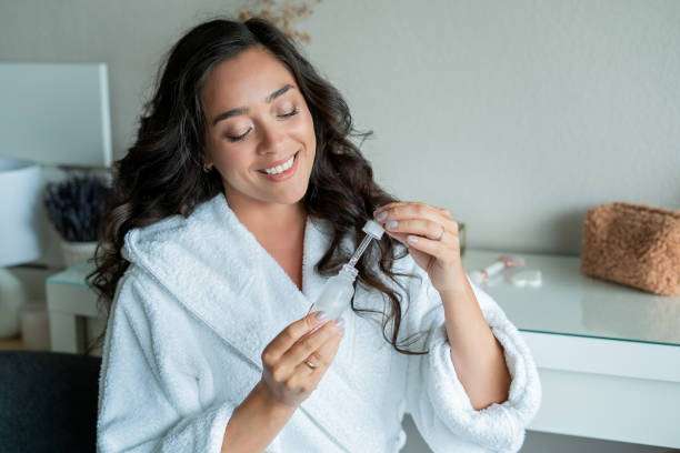 Woman smiling, applying hair oil with dropper