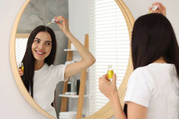 Young female adult standing in front of mirror in the bathroom at home after washing her hair oil