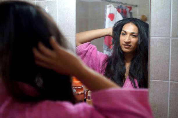 Woman applying hair oil to her healthy, long hair.