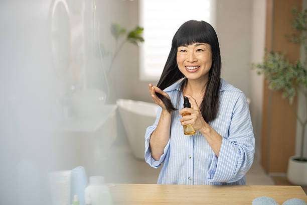 Young female adult standing in front of mirror in the bathroom at home after washing her hair oil
