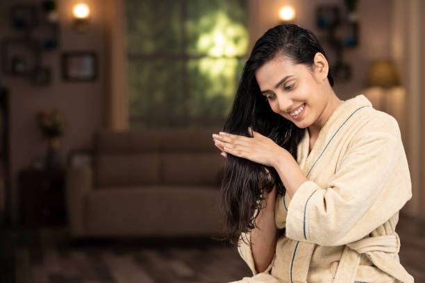 Young female adult standing in front of mirror in the bathroom at home after washing her hair oil