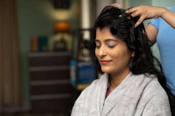Woman enjoying a scalp massage with hair oil treatment.