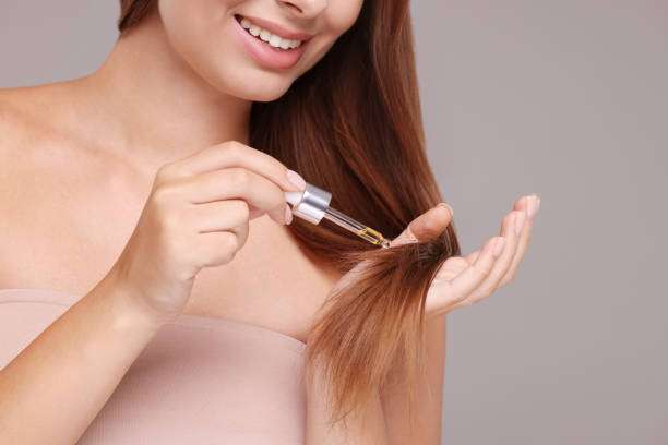 Close-up of woman applying luxurious hair oil to ends.