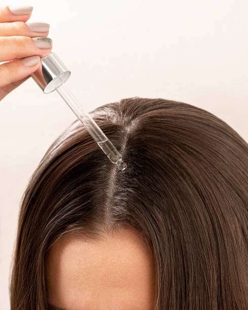 Close-up of hair oil dropper applying to scalp.